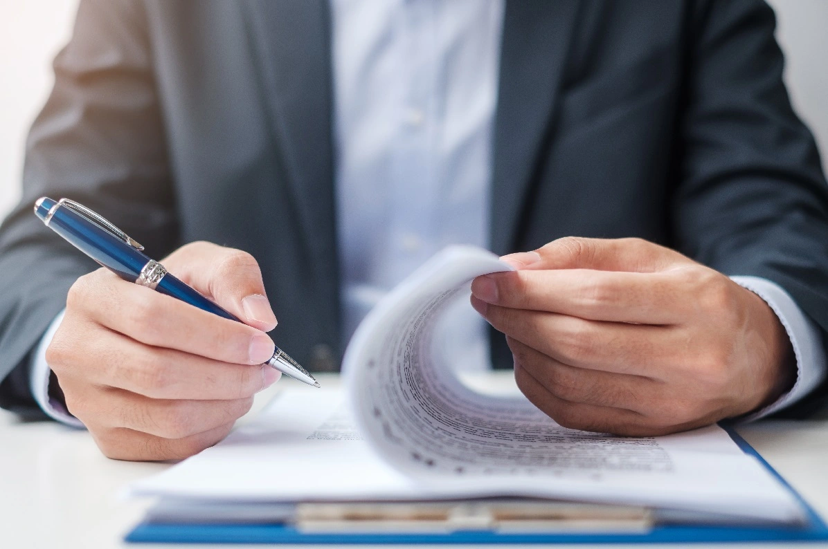 Homem de negócios assinando acordo contratual e revisando relatórios sobre como registrar nome de empresa.